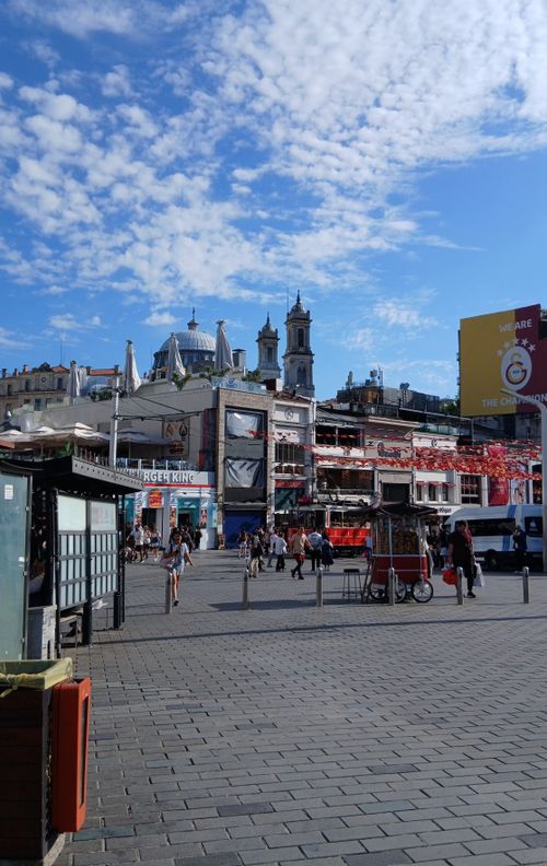 Free Bustling city square on a sunny day with historic architecture and vibrant street life. Stock Photo