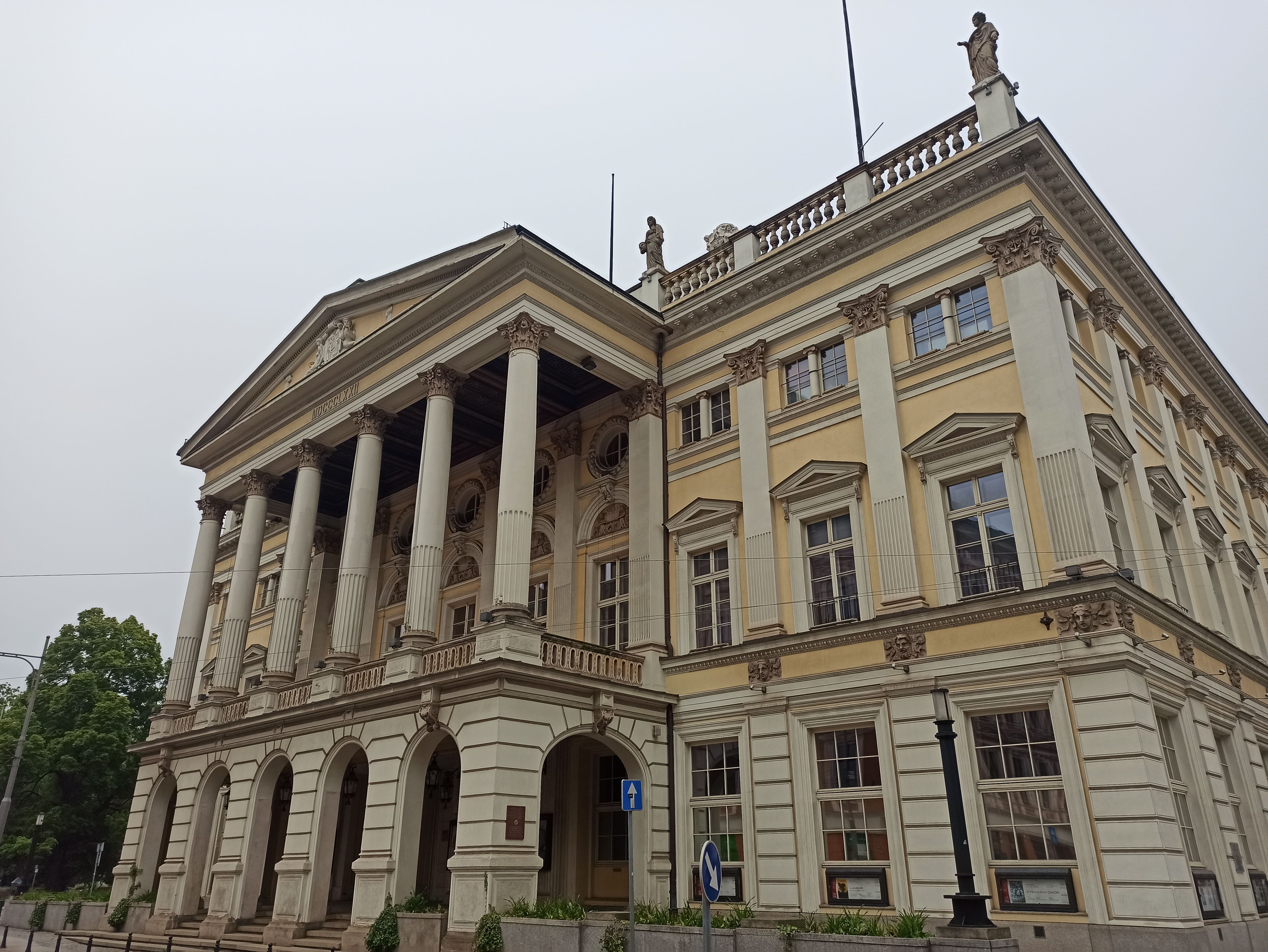 Elegant Neo-Classical building exterior on a cloudy day with columns and statues.