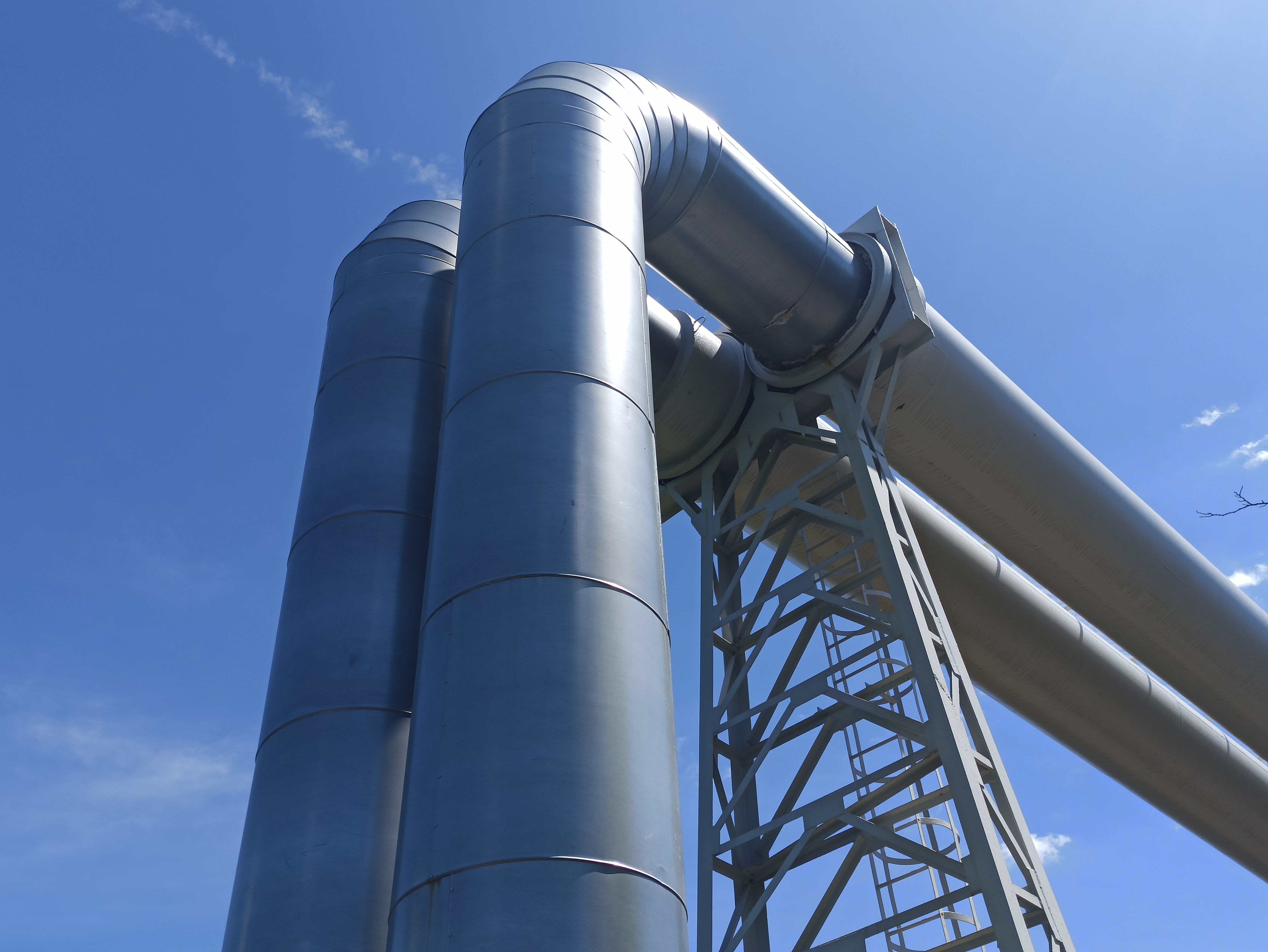 Large industrial steel pipes stacked under a blue sky