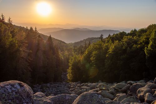 Free Stunning sunrise over a forest and rocky slope in mountain landscape. Perfect for nature and travel themes. Stock Photo