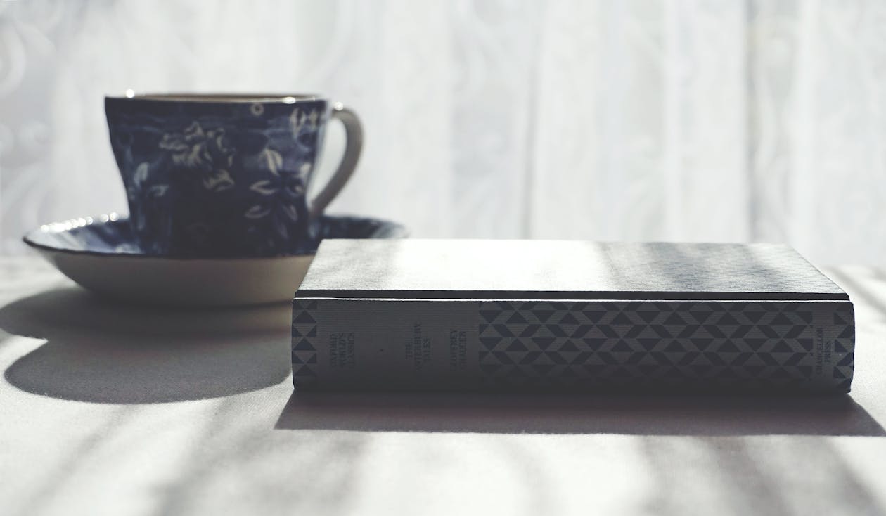 Ceramic Mug With Floral Design And Book onTable