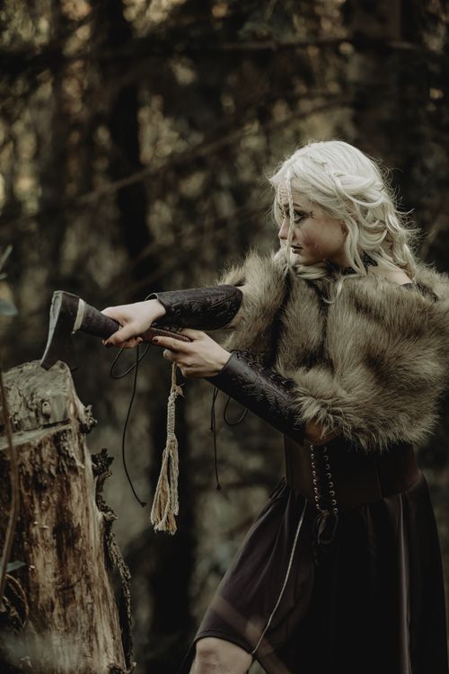 Free A fierce warrior woman with fur cape and axe in a mysterious forest Stock Photo