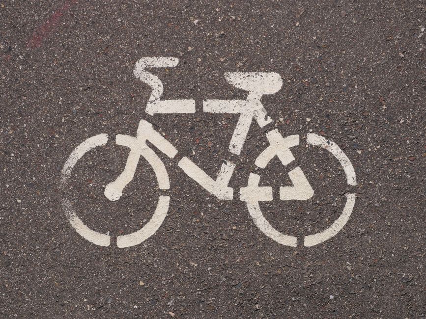 Close-up of a white bicycle lane marking on asphalt, showcasing urban cycling infrastructure.