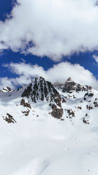 Breathtaking view of snowy mountains with clear blue sky and scattered clouds.