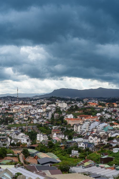 Free Panoramic view of Da Lat city with vibrant houses and dramatic cloudy sky, offering a picturesque Vietnamese landscape. Stock Photo