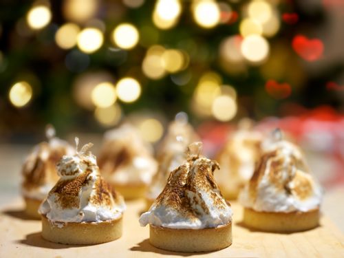 Free Toasted meringue tarts with a festive bokeh background, perfect for holiday celebrations. Stock Photo