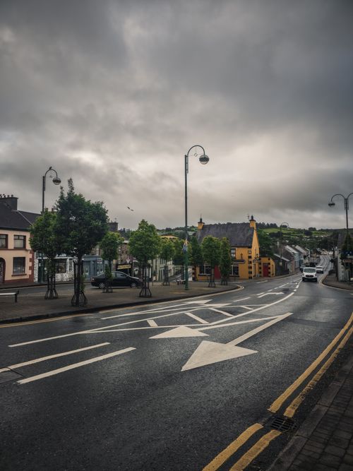 Free A serene Irish street under cloudy skies, showcasing local architecture and greenery. Stock Photo