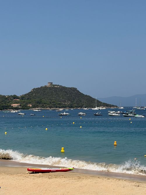 Free Serene beach view with boats and distant hills at Belvédère-Campomoro, Corsica. Stock Photo