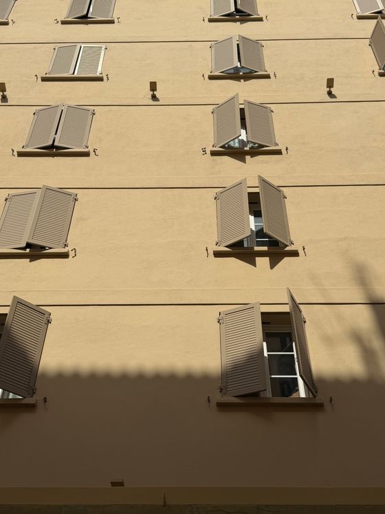 Beige building facade with open shutters, photo by Dark Astraal on Pexels
