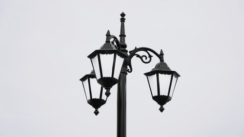 Free Elegant black street lamp with intricate designs set against an overcast sky, showcasing traditional street lighting. Stock Photo