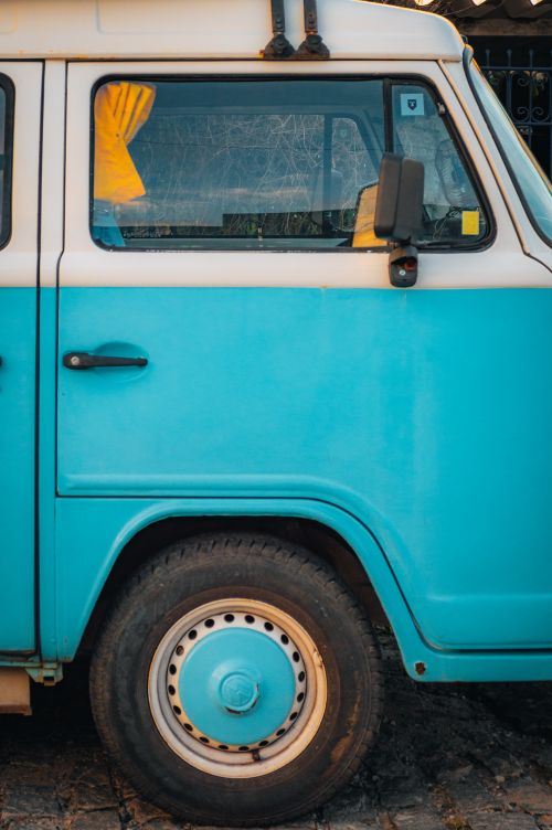 Free Close-up of a retro turquoise camper van, showcasing its side panel and wheel. Stock Photo