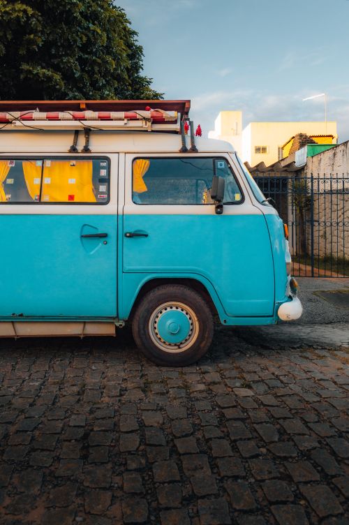 Free Brightly colored vintage camper van parked on a cobblestone street in Natal, Brazil. Stock Photo