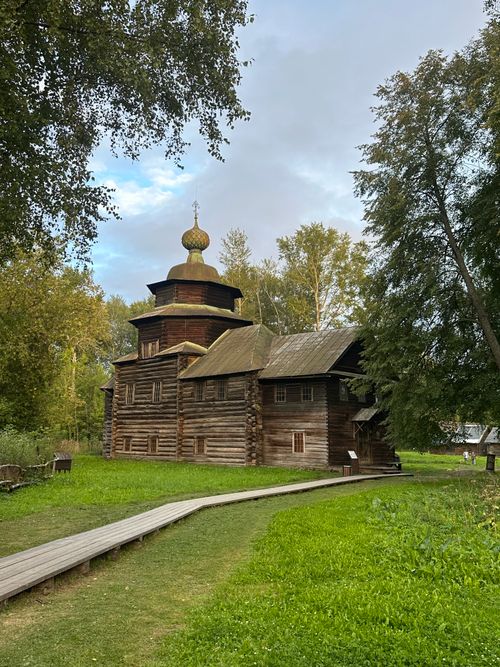 Free A wooden church set against a lush green landscape under a cloudy sky. Stock Photo