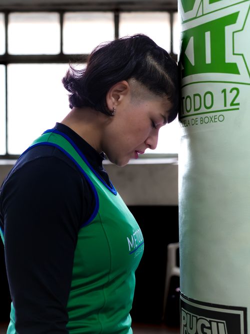 Free Focused female boxer leaning against a punching bag in a Buenos Aires gym. Stock Photo