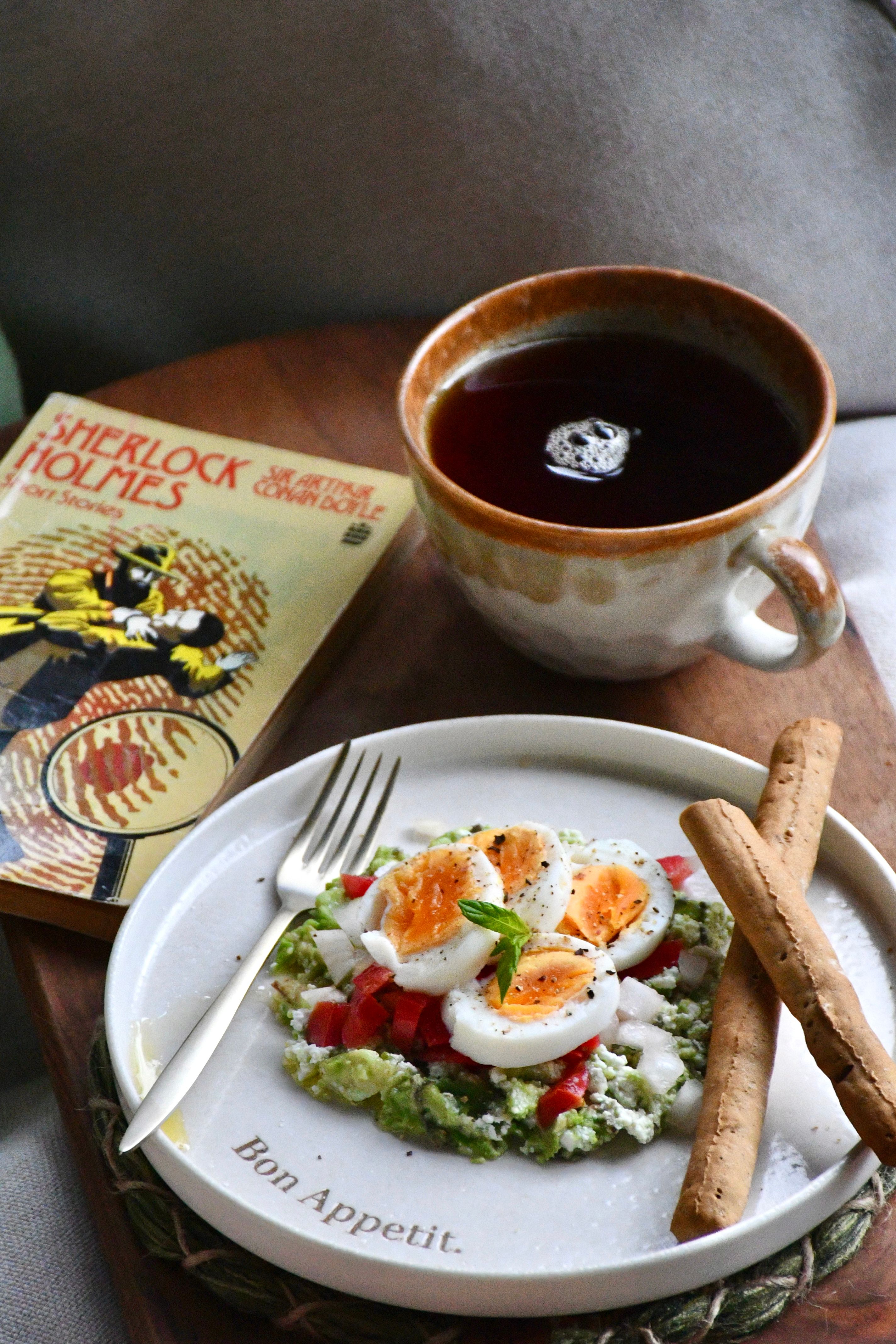 A cozy breakfast setting with tea, toast, and Sherlock Holmes book on a wooden tray.