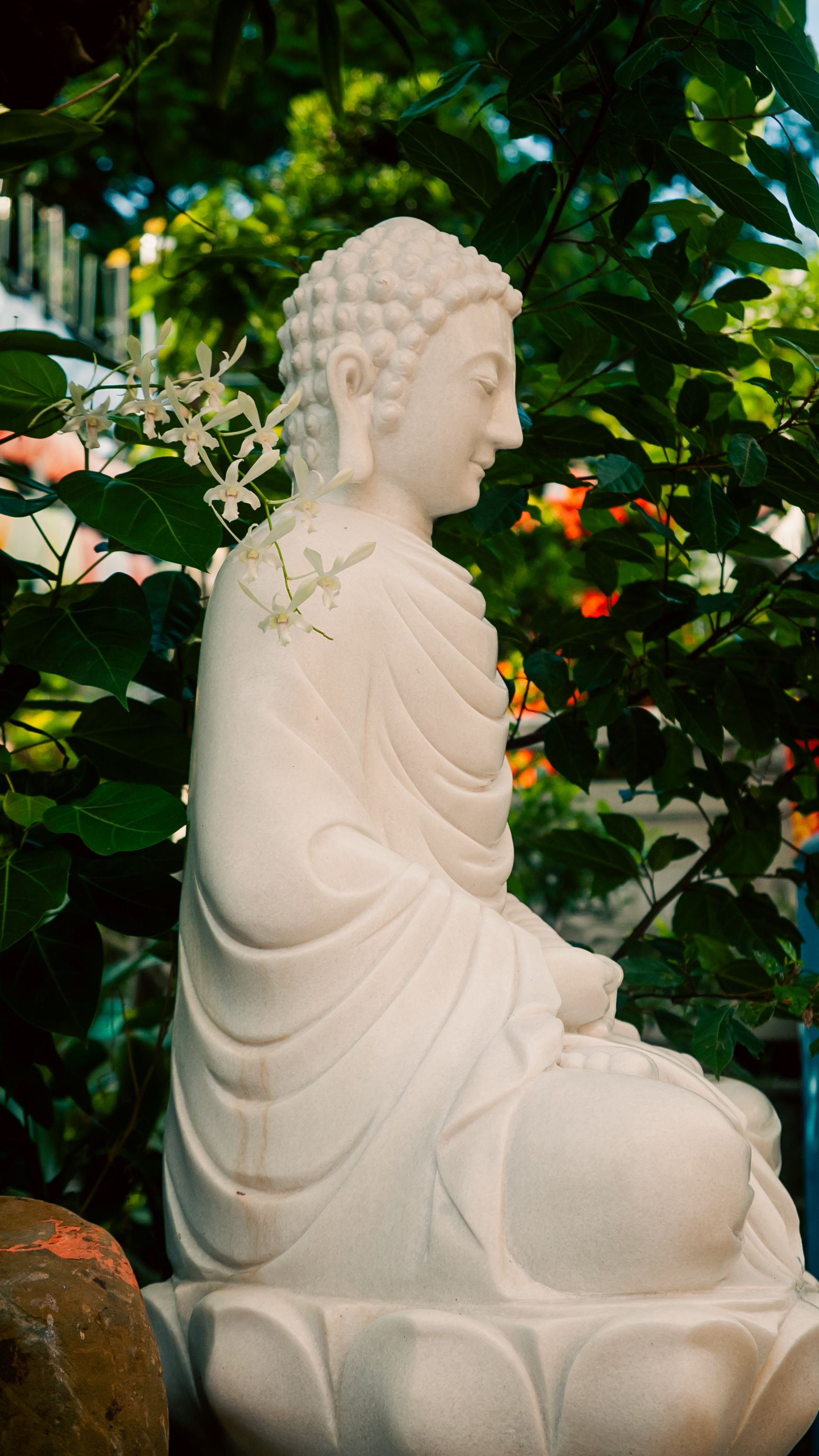 White marble Buddha statue surrounded by vibrant greenery in Ho Chi Minh City, Vietnam.
