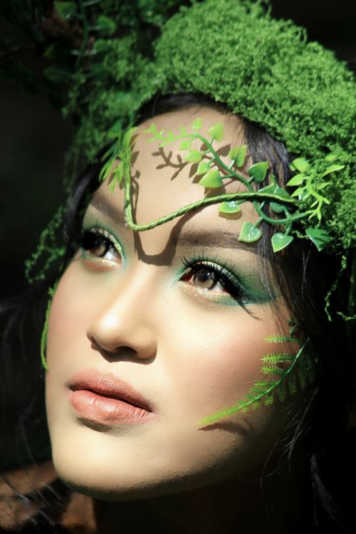 Free A captivating portrait featuring nature-inspired makeup amidst greenery. Stock Photo