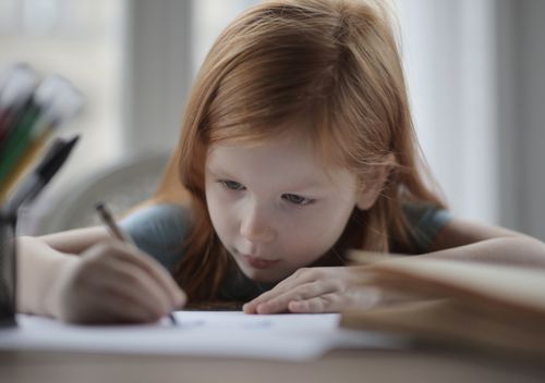 Free A young girl intently writing while doing homework indoors, symbolizing concentration and learning. Stock Photo