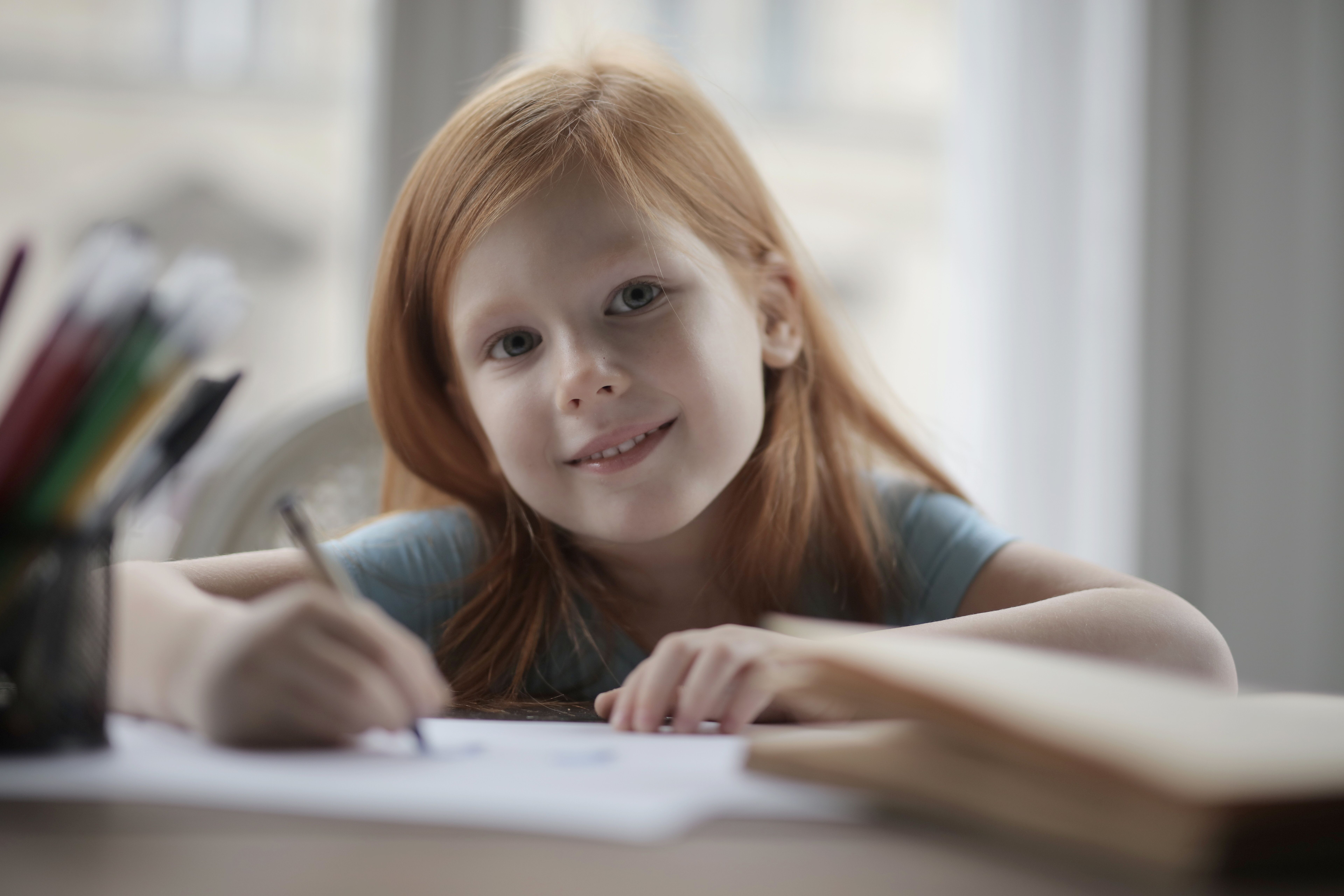A joyful young girl drawing with crayons, showcasing creativity indoors. - Photo by Andrea Piacquadio on Pexels