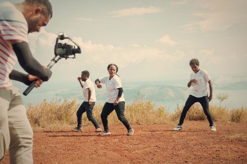 Free Group of men dancing outdoors while cameraman films on rocky terrain. Stock Photo