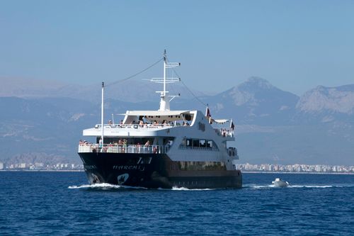 Free A ferry sails on the Mediterranean Sea with mountains in the background, showcasing a serene voyage. Stock Photo