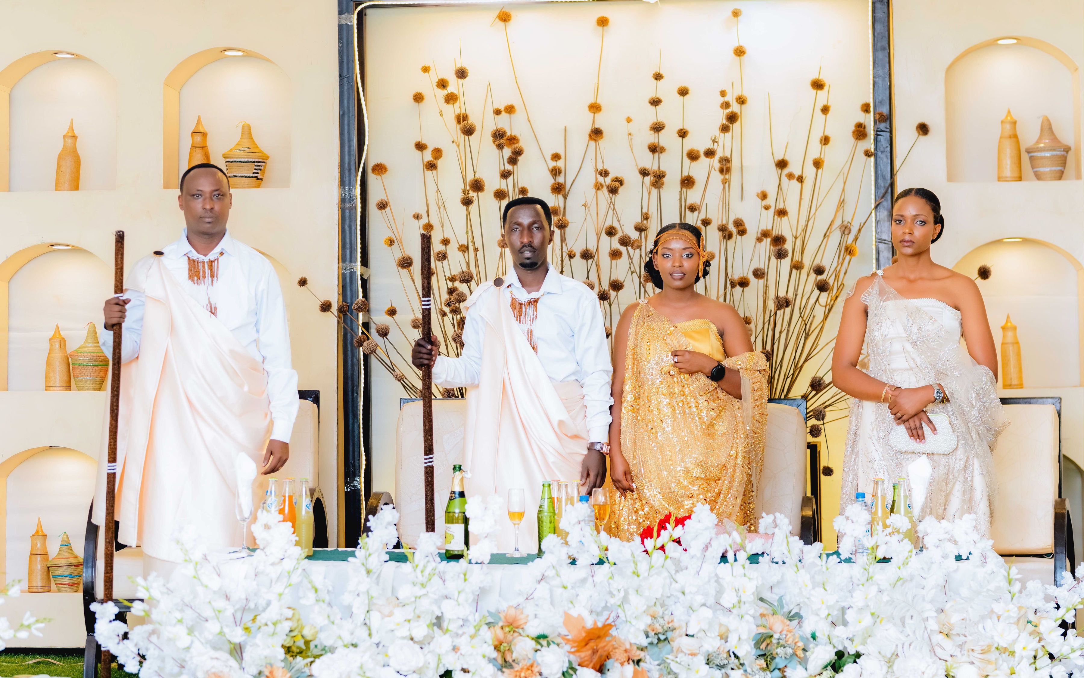 Group of adults in elegant traditional African attire posing indoors at a wedding ceremony.
