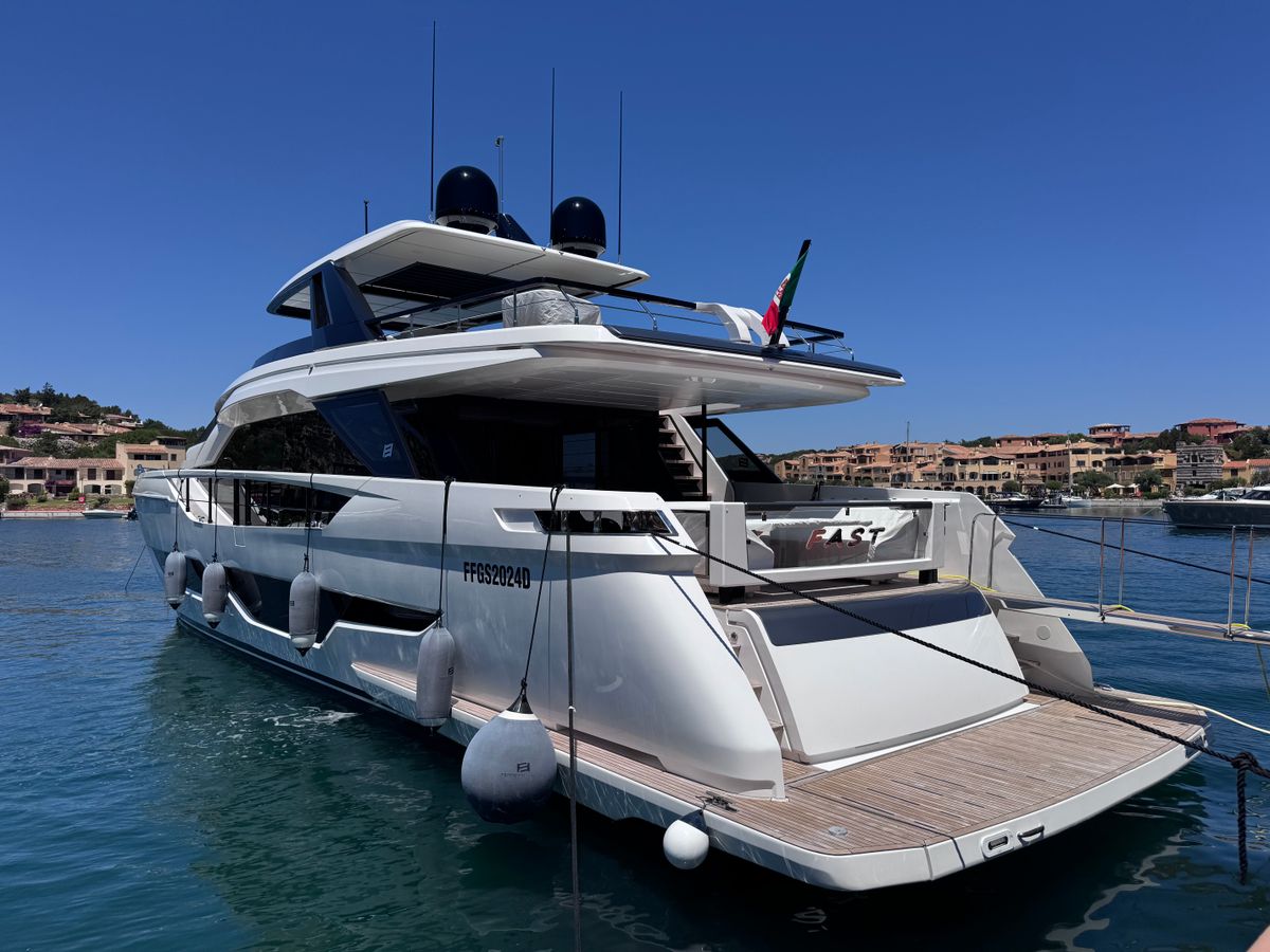 Iaht de lux acostat, cu satul Costa Smeralda in fundal