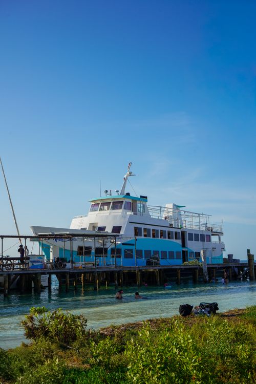 Free A stunning view of a ferry docked at a wooden pier on a clear, sunny day with vibrant blue skies. Stock Photo