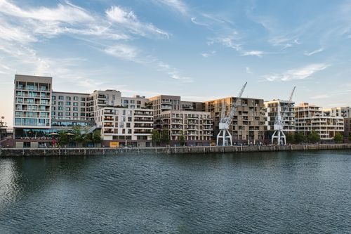 Free Contemporary apartment buildings along a waterfront with cranes at dusk. Stock Photo