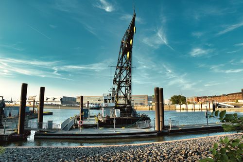 Free Dynamic shot of an industrial crane at a river port during a bright summer day. Stock Photo
