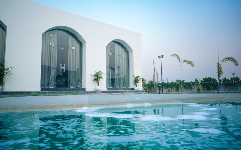 Resort villa with arched glazing, deck and swimming pool surrounded by palm trees