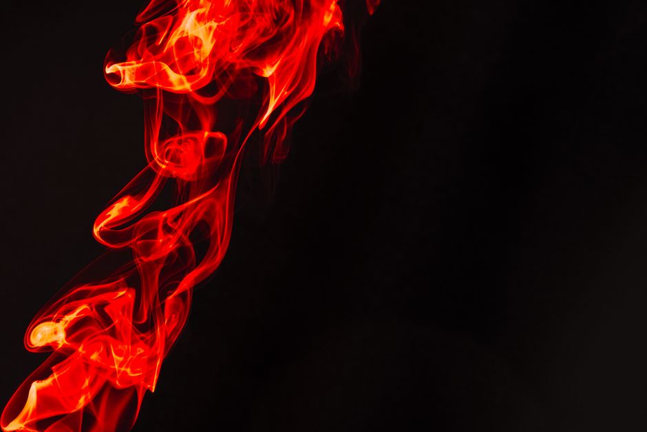 Fotomural Ilustración abstracta de humo rojo intenso que se arremolina elegantemente sobre un fondo negro oscuro, ideal para proyectos creativos con espacio para texto.