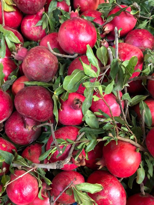 Free Vibrant display of fresh red pomegranates with lush green leaves, showcasing natural beauty. Stock Photo