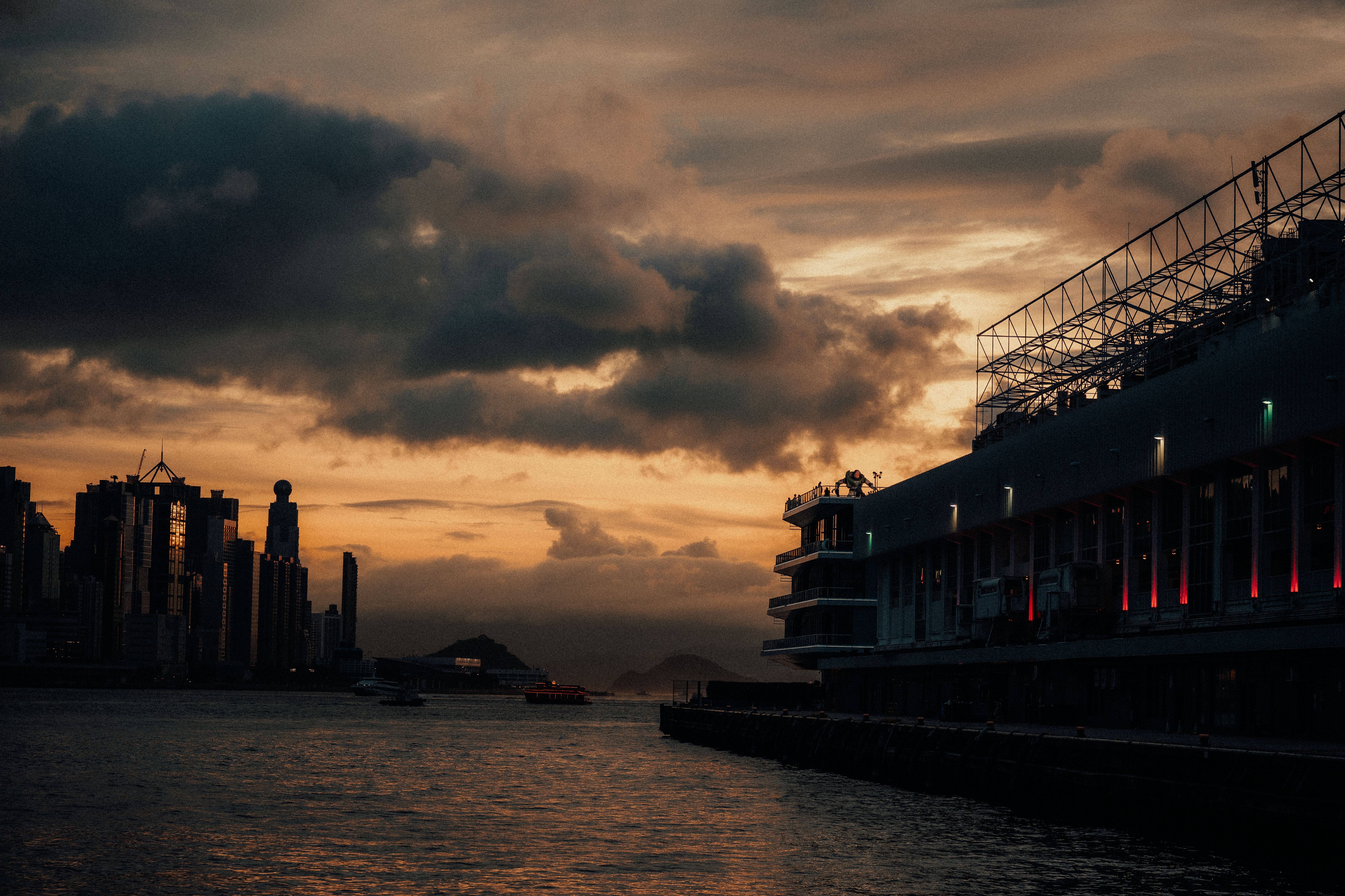 A Hong Kong racecourse at dusk with horses approaching the finish line and spectators studying race cards