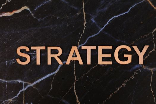 Strategic planning concept with 'Strategy' in wooden letters on dark marble.