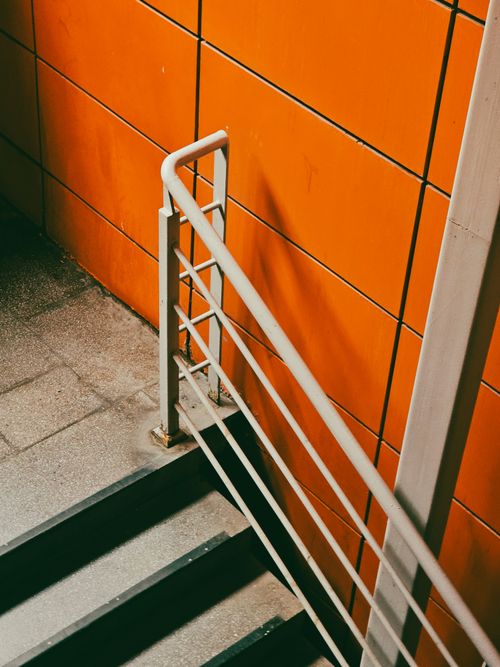 Free Industrial staircase with vibrant orange wall, creating modern urban aesthetic. Stock Photo