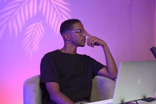 Free Person in modern workspace with thoughtful expression, vibrant lighting. Stock Photo