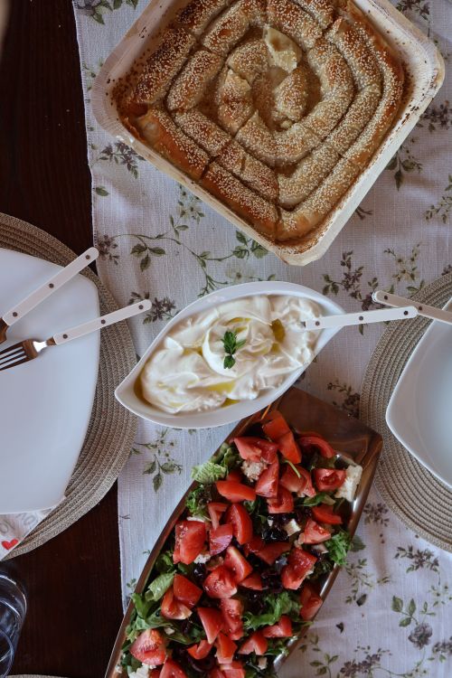 Free A delectable Greek meal featuring spinach pie, yogurt, and fresh salad, beautifully arranged on a dining table. Stock Photo