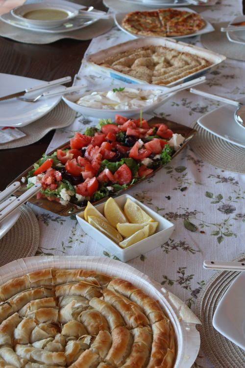 Free A beautifully arranged Greek meze spread featuring fresh salad, lemon wedges, and various traditional dishes. Stock Photo