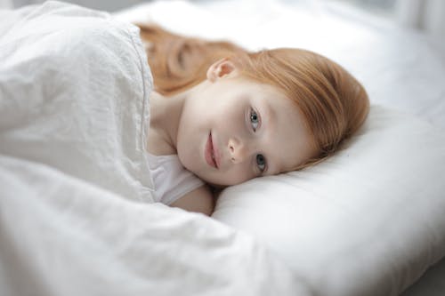 Girl Lying on White Bed