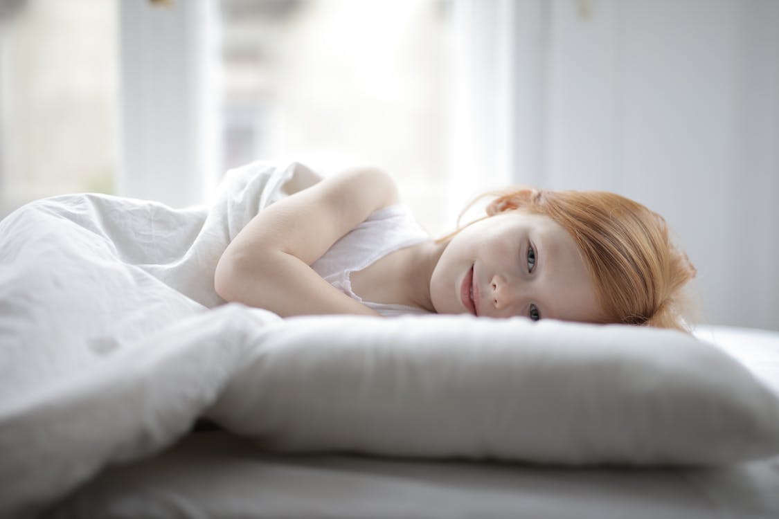 Free Girl Lying on White Bed Stock Photo