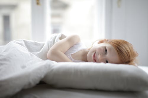 Girl in White Tank Top Lying on Bed