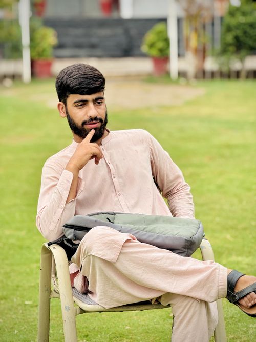 Free A man sitting casually on a chair in a garden, enjoying a sunny day. Stock Photo