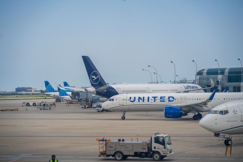 Free A view of diverse airplanes alongside a busy airport terminal and runway. Stock Photo