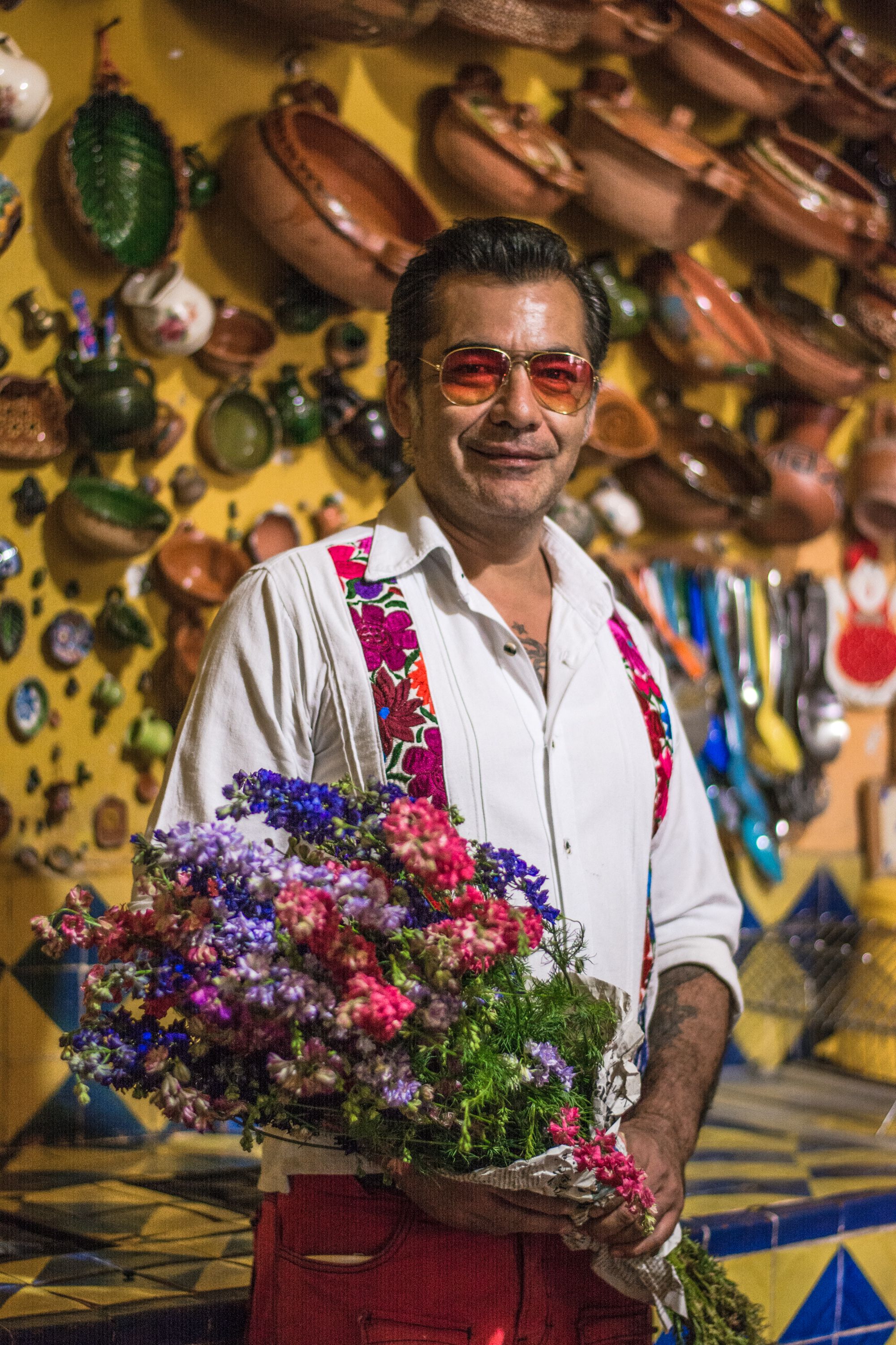 Colorful portrait of a man holding flowers in a vibrant Oaxacan market.