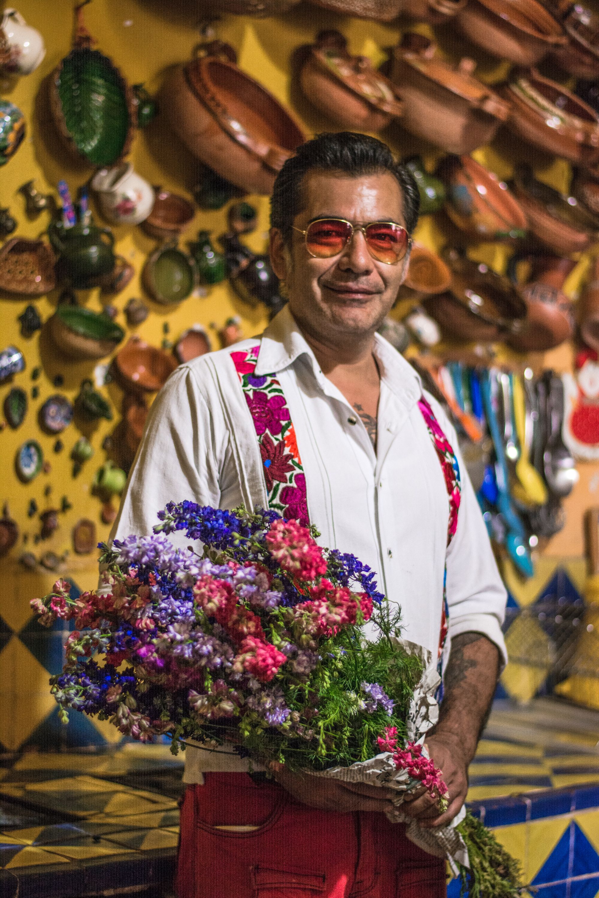 A vibrant portrait of a man holding a bouquet in a traditional Oaxaca market setting.