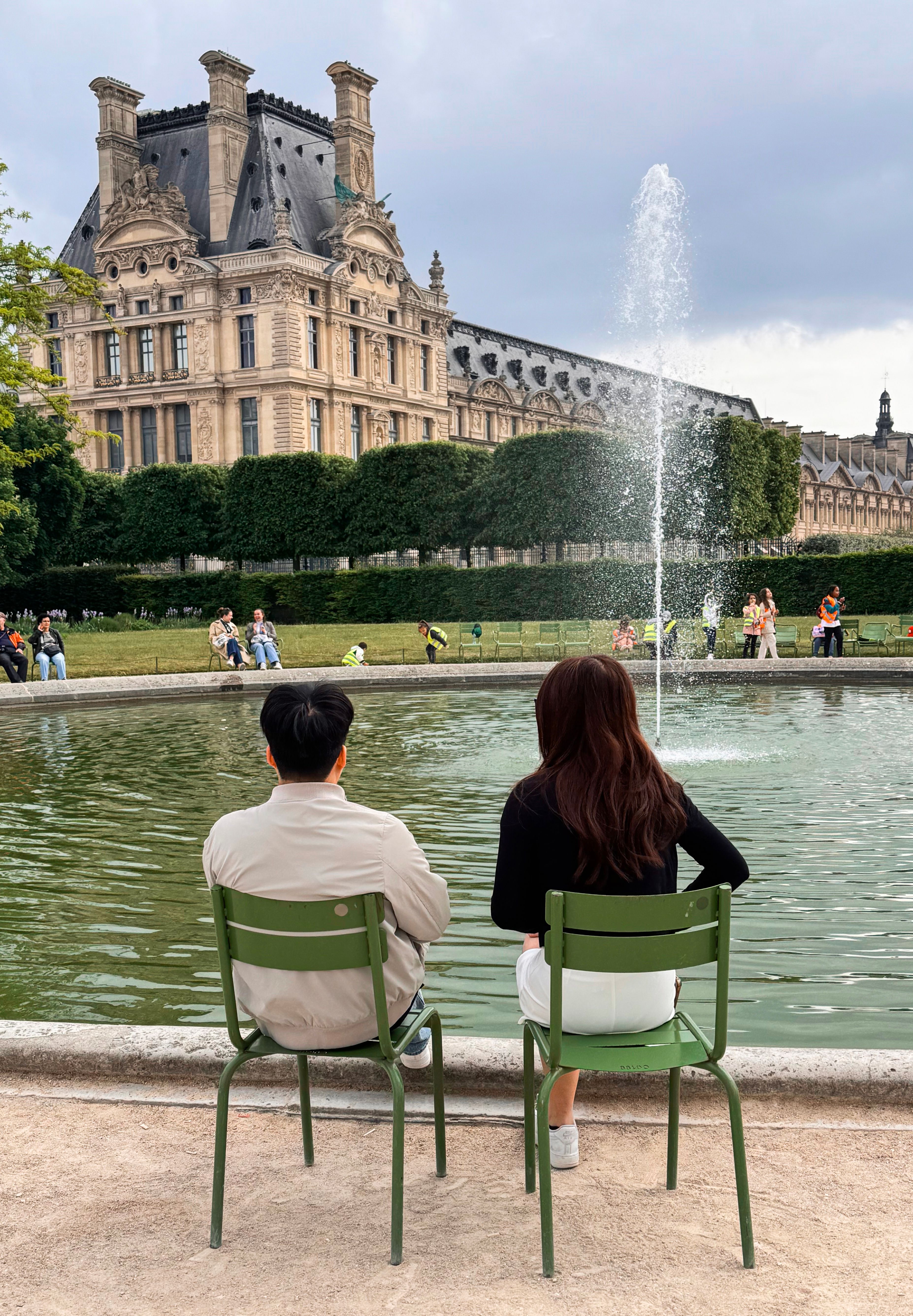 A couple enjoys a peaceful moment by the fountain at the Louvre, Paris.