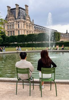 A couple enjoys a peaceful moment by the fountain at the Louvre, Paris.