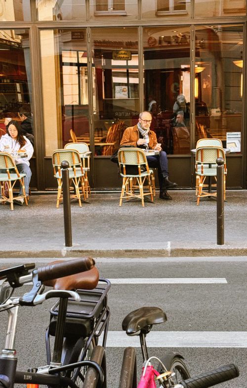 Free A Parisian cafe with patrons sitting outdoors enjoying a quiet afternoon. Stock Photo