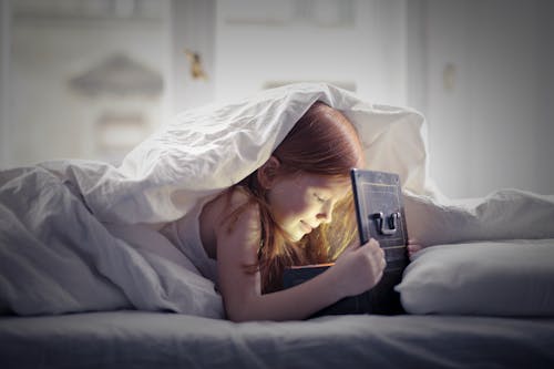 Free Girl Lying on Bed Looking At An Open Lighted Box Stock Photo